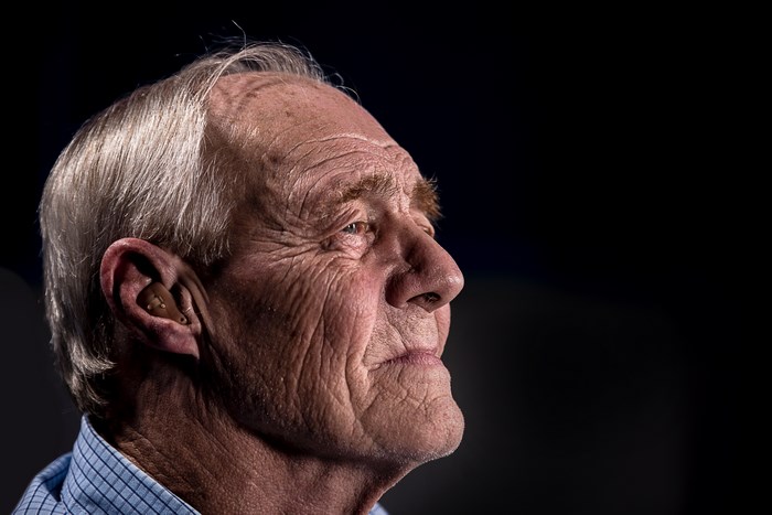 Elderly man with hearing aid in profile