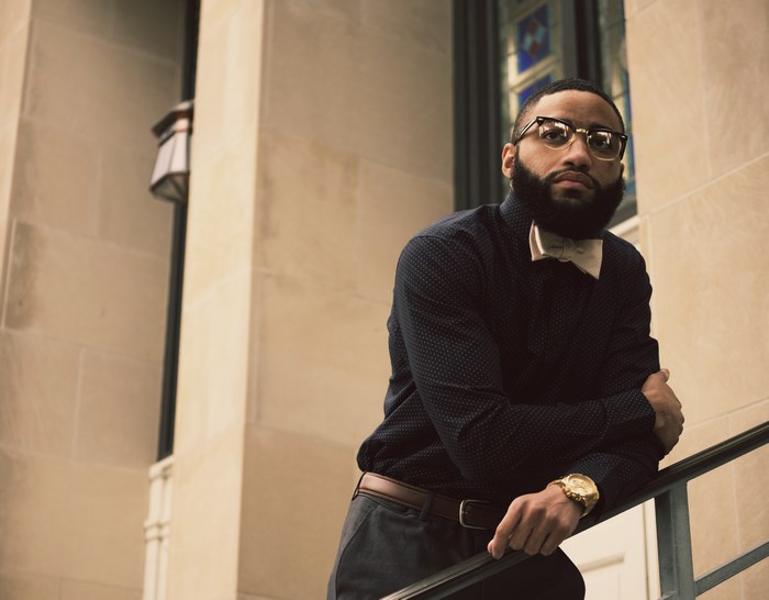 Man in bow tie leaning on stairs outside building