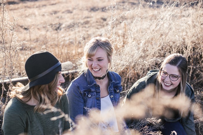 Three women laughing in a dry field