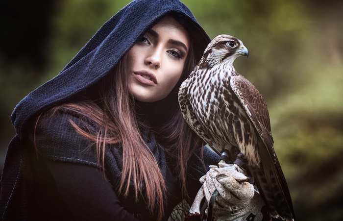 Woman in a hood with a falcon on her arm