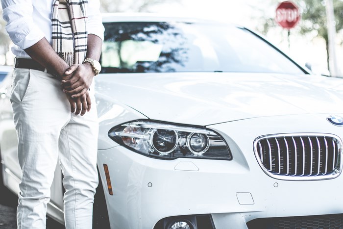 Man in scarf standing by a white BMW car