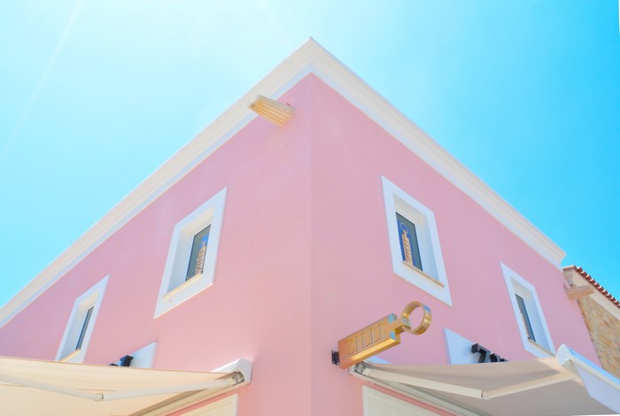Pink building corner with windows and a sign in Limassol, Cyprus