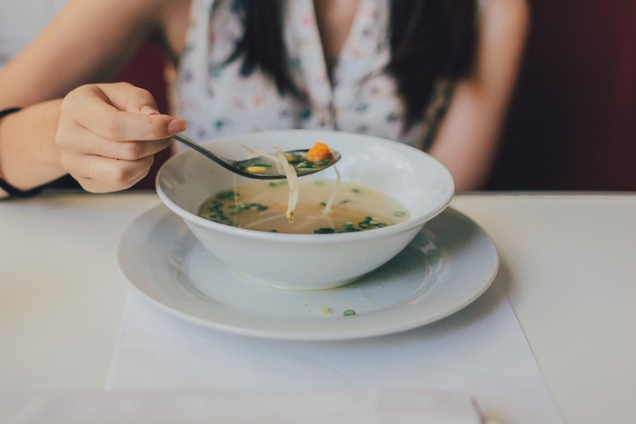 Woman eating soup with beansprouts and carrots