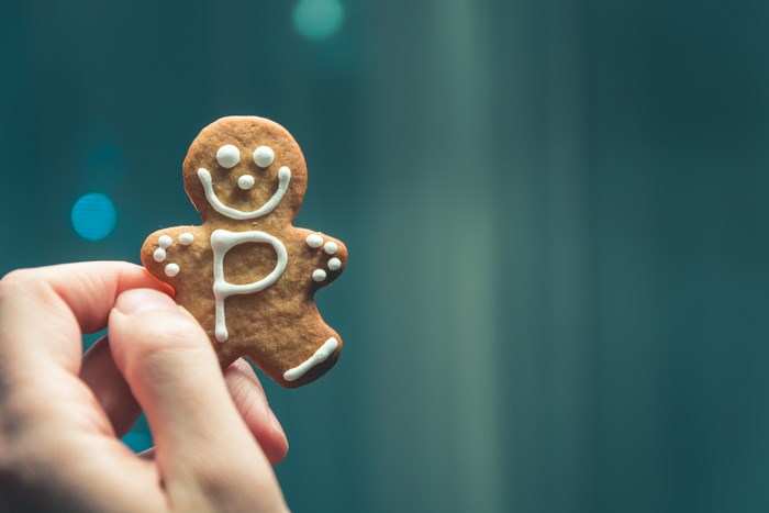 Gingerbread man cookie with letter P held by a hand