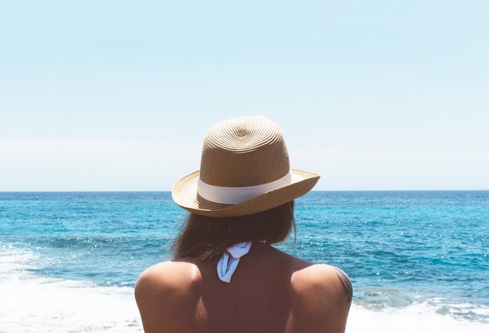 Woman in straw hat looking at the ocean