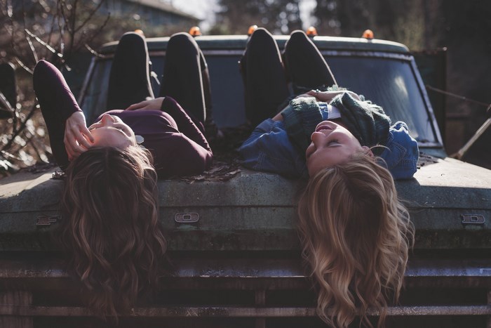 Two women lying on the hood of a vintage Ford truck