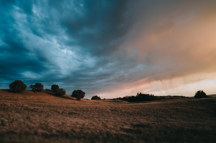 Stormy sky over a grassy field with trees