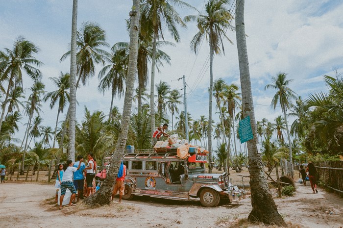 Jeepney loaded with goods under palm trees