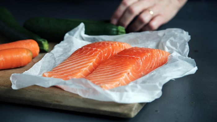 Salmon fillets on baking paper with carrots and zucchini