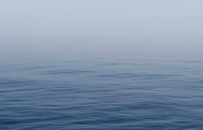 Calm blue water in dense mist