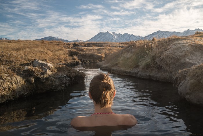 Woman bathing in a hot spring with snowy mountains in the background