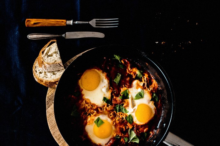 Shakshuka in a skillet with bread and cutlery
