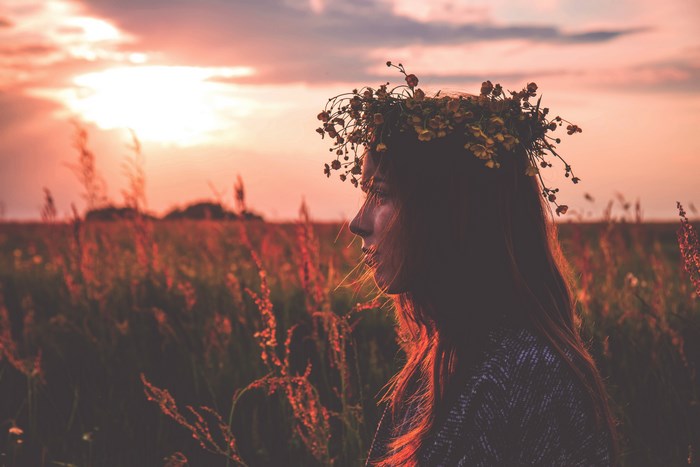 Woman with flower crown in a field at sunset