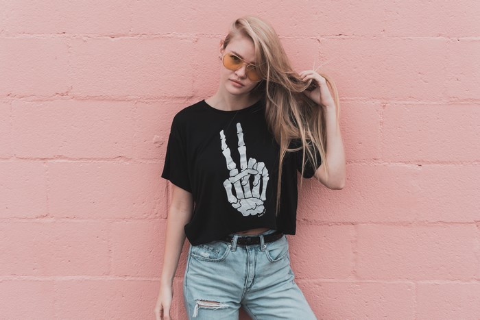 Woman in black t-shirt with peace sign on pink wall