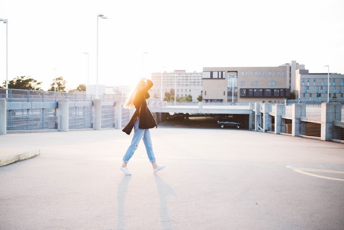 Woman walking in a parking garage during golden hour