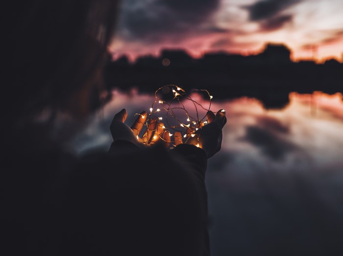 Hands holding fairy lights at sunset