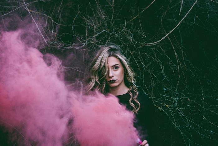 Woman with pink smoke grenade in forest