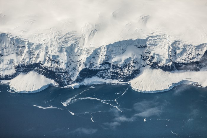 Aerial view of a snow-covered glacier meeting the ocean