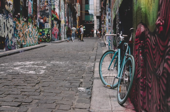 Blue bicycle parked in a graffiti-covered Melbourne laneway