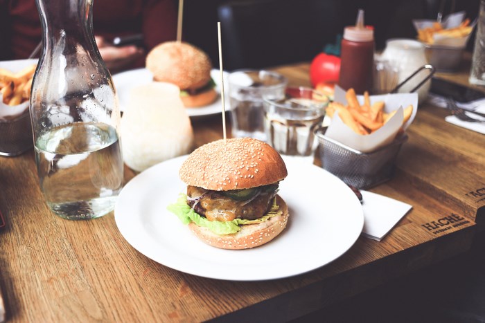 Hamburger with fries and water on a wooden table