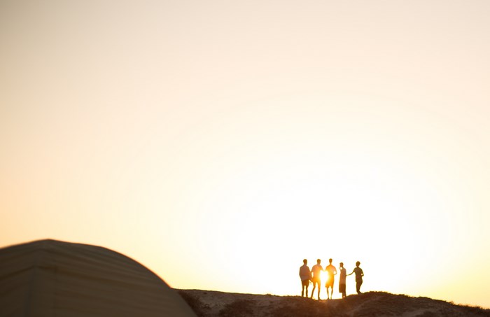 Group of friends silhouetted against a golden sunset on a hill