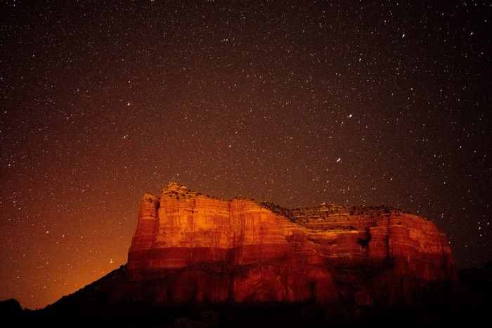 Red rock formation under a starry night sky