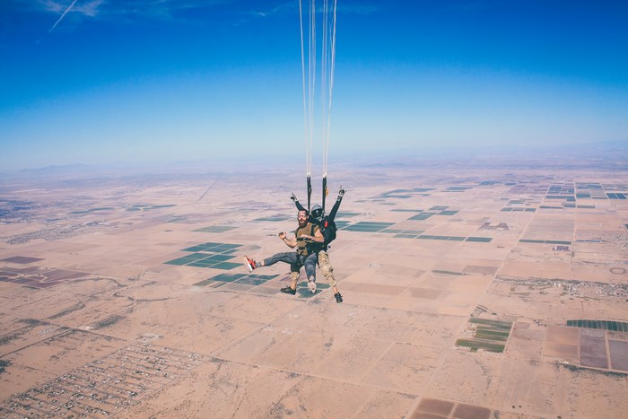 Tandem skydivers enjoying a jump over a desert landscape