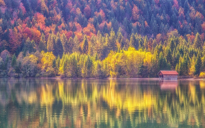 Autumn forest reflected in a lake with a boathouse