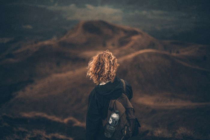 Woman with red hair and backpack on a hillside
