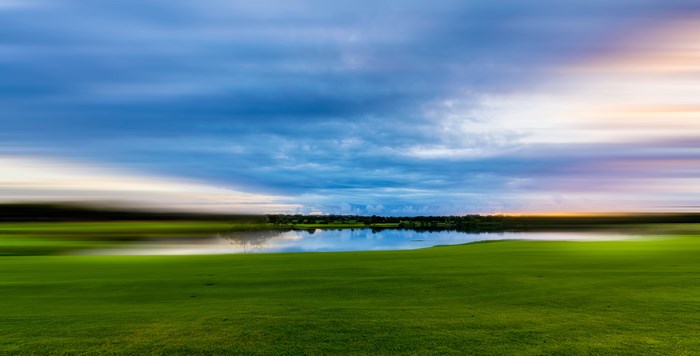 Long exposure landscape of a lake and green field at sunset