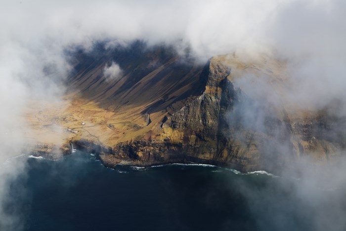 Aerial view of a misty coastline with a waterfall and mountains