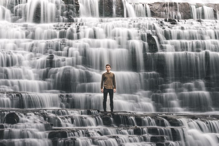 Man standing in front of a cascading waterfall