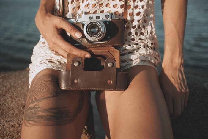 Woman holding a vintage camera with a tattoo