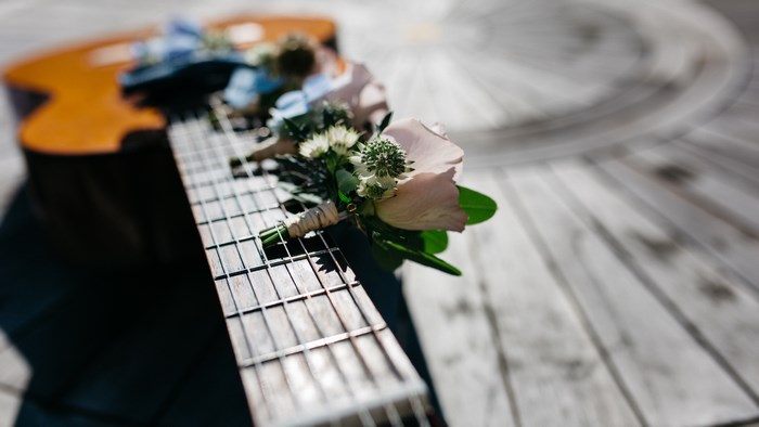 Acoustic guitar with flowers on wooden surface