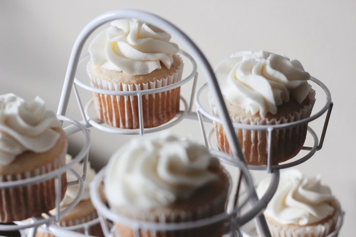 White cupcakes with frosting on a cake stand