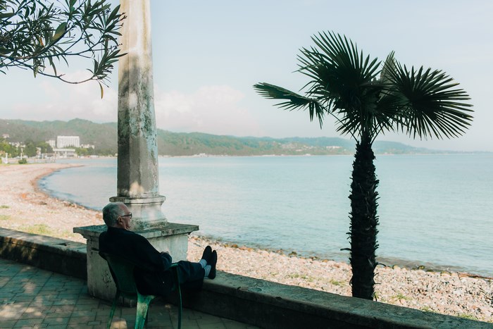 Elderly man resting on a balcony overlooking the sea