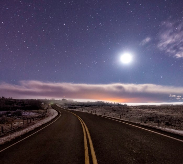 A Winding Road Under a Starry Night Sky with the Moon