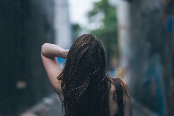 Woman with long brown hair in an alleyway