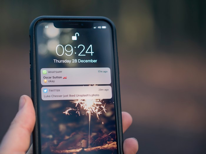 Hand Holding Smartphone Showing Notifications on Screen