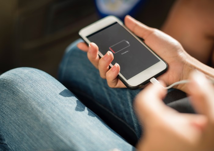 Person charging an iPhone with a low battery