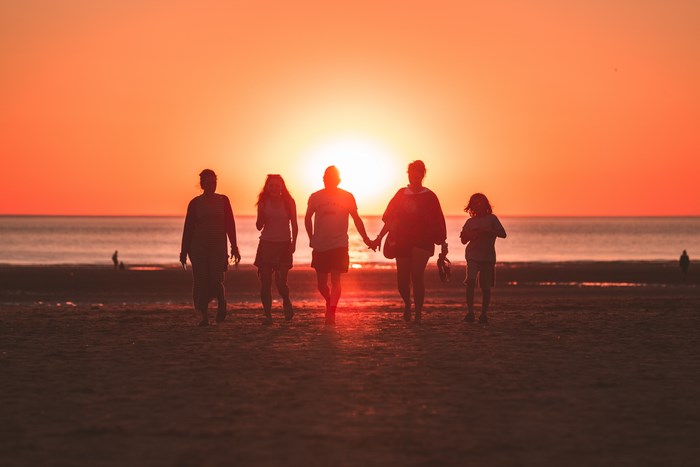 Family walking on beach at sunset