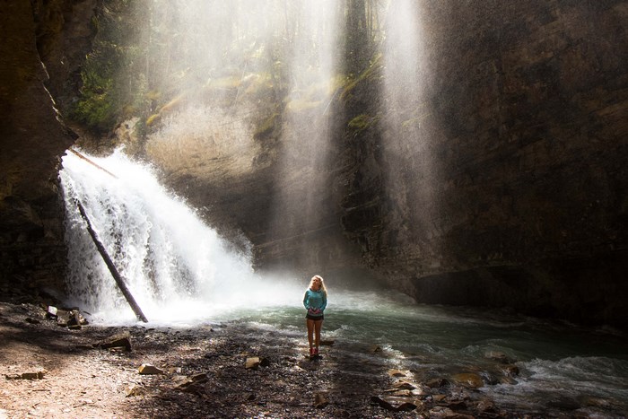 Woman standing near a waterfall in a canyon
