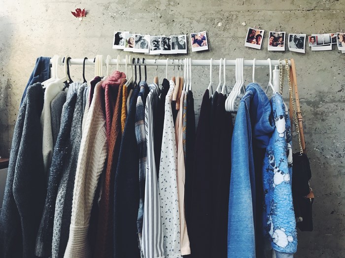 Clothes hanging on a rack in front of a concrete wall