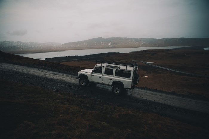 White Land Rover Defender driving on a dirt road in Iceland