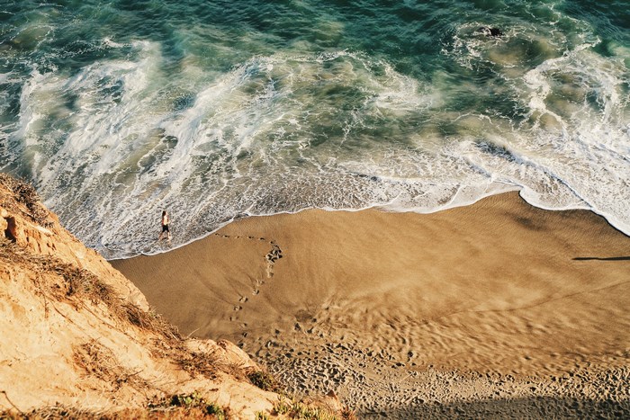 Person walking on a sandy beach by the ocean