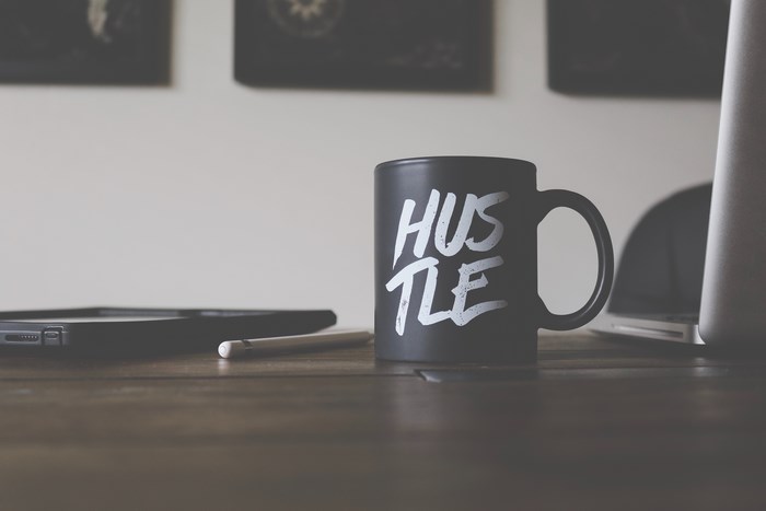 Black mug with "Hustle" text on a desk