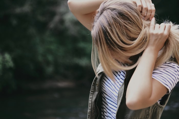 Woman holding her blonde hair outdoors