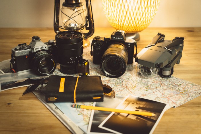 Travel gear: cameras, drone, notebook, map, and lantern