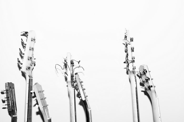 Monochrome image of guitar heads against a white wall