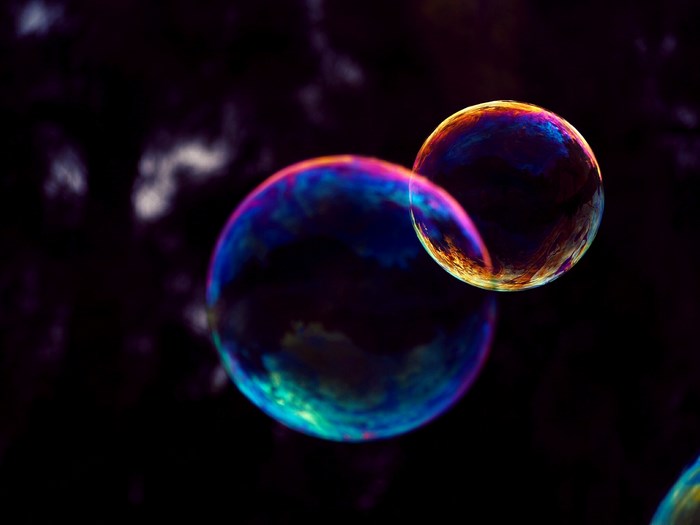 Two colorful iridescent bubbles floating against a dark background